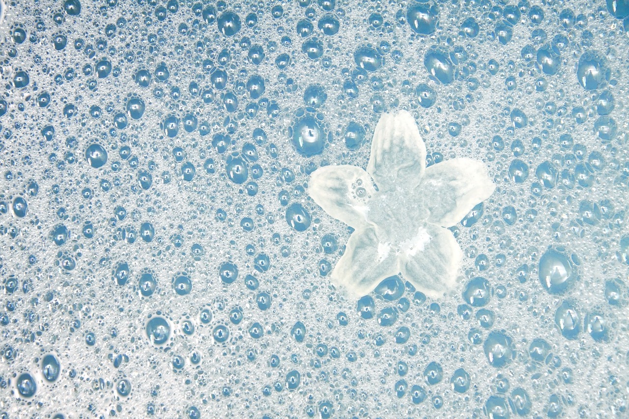 sali di Epsom e cloruro di Magnesio: uno sfondo di gocce d'acqua azzurre e un fiore stilizzato in primo piano